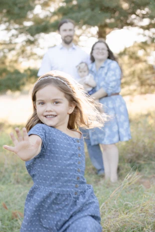 Young girl running toward the camera during a family session in Omaha, NE