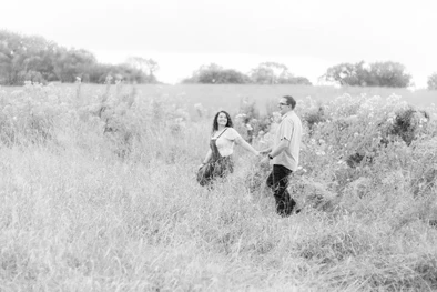 A couple walking across a field during engagement photos in Omaha