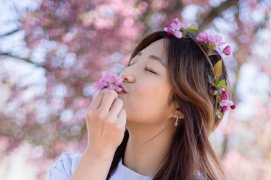 A young girl smelling flowers during her spring senior session in Omaha, NE