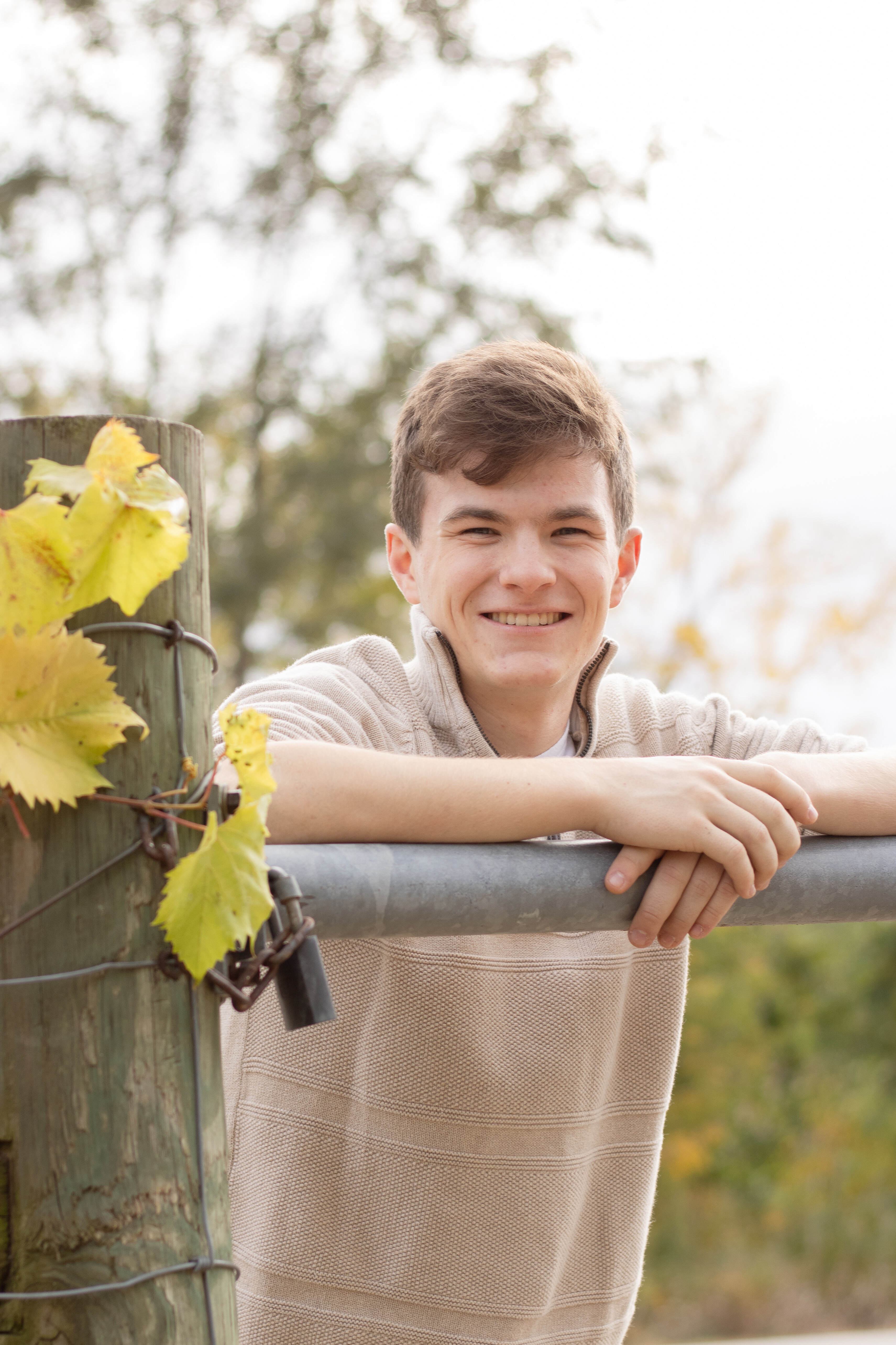 Boy leaning over a leaf-covered fence during his Omaha senior session